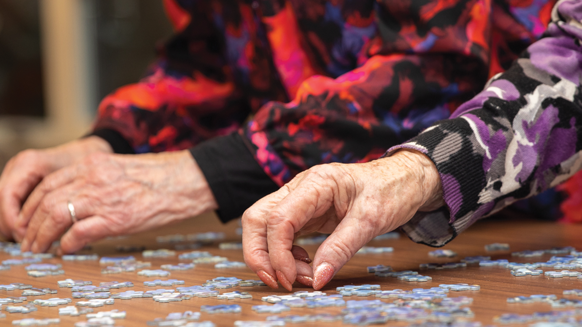 Hands of two elderly women doing a  puzzle a hobby for the elderly