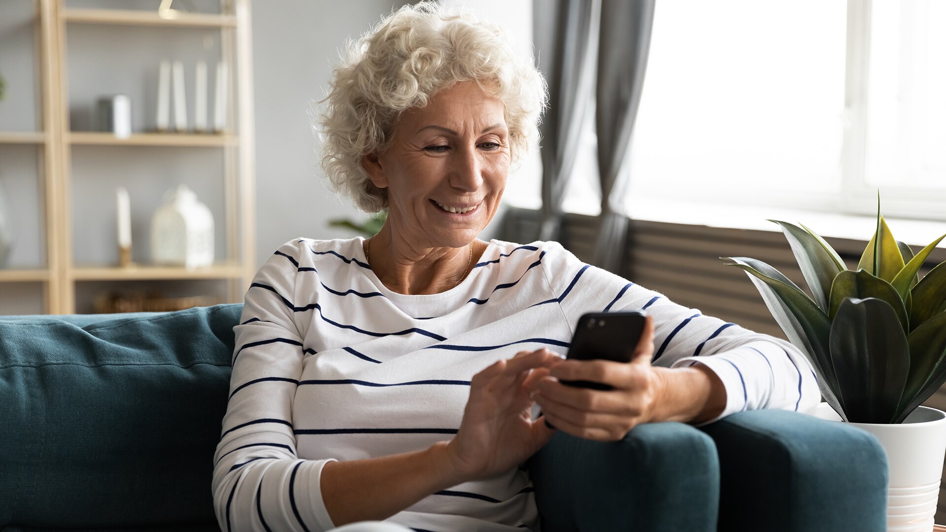An elderly lady smiling while using mobile in independent living